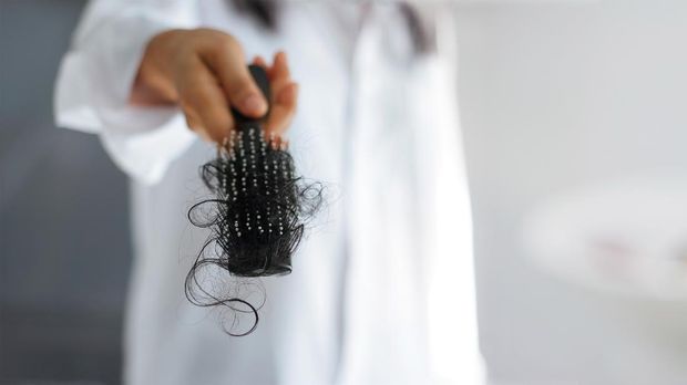 closeup woman hand holding hair fall from hairbrush