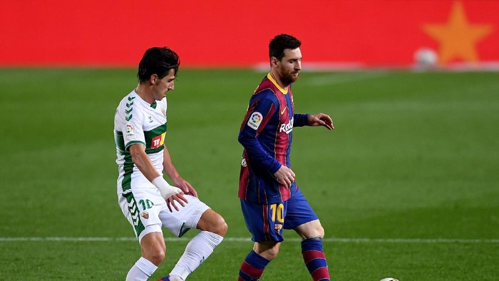 BARCELONA, SPAIN - FEBRUARY 24: Lionel Messi of FC Barcelona passes the ball whilst under pressure from Pere Milla of Elche CF during the La Liga Santader match between FC Barcelona and Elche CF at Camp Nou on February 24, 2021 in Barcelona, Spain. Sporting stadiums around Spain remain under strict restrictions due to the Coronavirus Pandemic as Government social distancing laws prohibit fans inside venues resulting in games being played behind closed doors. (Photo by Alex Caparros/Getty Images)