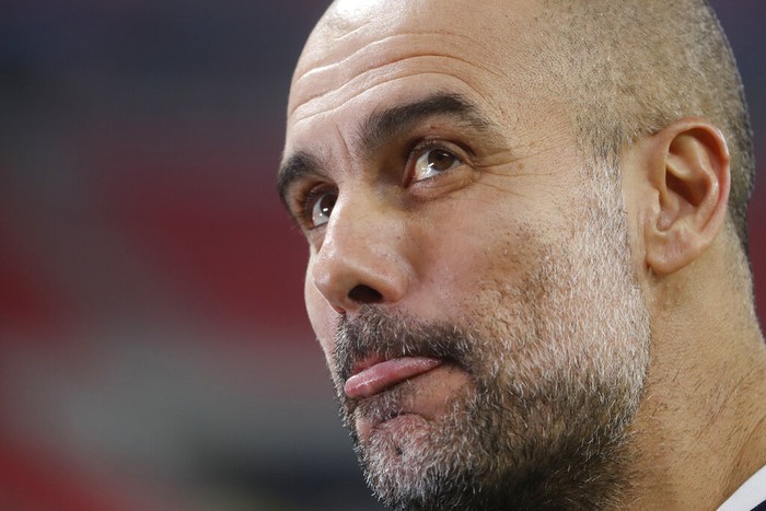 Manchester Citys head coach Pep Guardiola grimaces ahead of the Champions League round of 16 first leg soccer match between Borussia Monchengladbach and Manchester City at the Puskas Arena stadium in Budapest, Hungary, Wednesday, Feb. 24, 2021. (AP Photo/Laszlo Balogh)