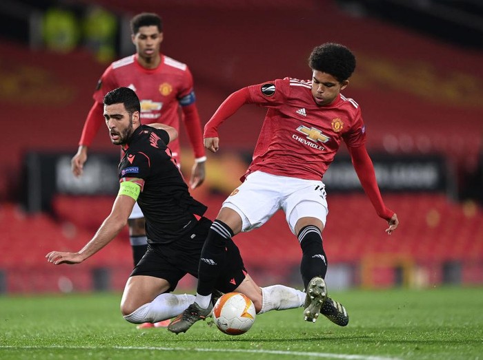 MANCHESTER, ENGLAND - FEBRUARY 25: Mikel Merino of Real Sociedad is tackled by Shola Shoretire of Manchester United during the UEFA Europa League Round of 32 match between Manchester United and Real Sociedad at Old Trafford on February 25, 2021 in Manchester, England. Sporting stadiums around the UK remain under strict restrictions due to the Coronavirus Pandemic as Government social distancing laws prohibit fans inside venues resulting in games being played behind closed doors. (Photo by Laurence Griffiths/Getty Images)