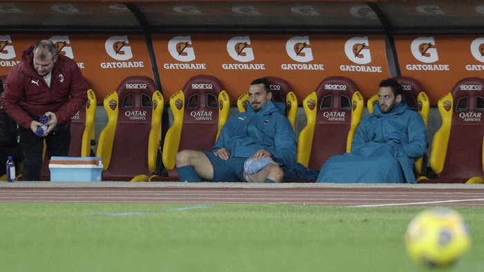 AC Milans Zlatan Ibrahimovic, centre, sits in the dug out with an ice pack on this leg after being substituted during the Serie A soccer match between AS Roma and AC Milan at the Olympic stadium, in Rome, Italy, Sunday, Feb. 28, 2021.(AP Photo/Gregorio Borgia)
