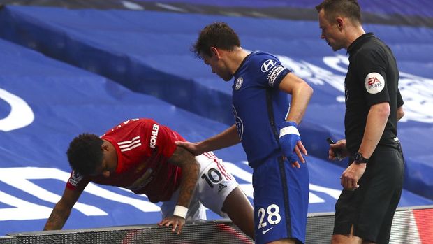 Manchester United's Marcus Rashford, left, is helped by Chelsea's Cesar Azpilicueta, centre, after colliding with an advertising board during the English Premier League soccer match between Chelsea and Manchester United at Stamford Bridge Stadium in London, England, Sunday, Feb. 28, 2021. (Clive Rose/Pool via AP)