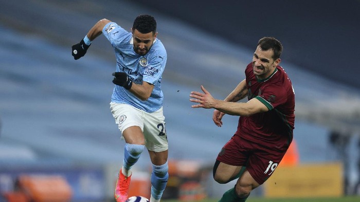 MANCHESTER, ENGLAND - MARCH 02: Jonny of Wolverhampton Wanderers and Riyad Mahrez of Manchester City battle for possession during the Premier League match between Manchester City and Wolverhampton Wanderers at Etihad Stadium on March 02, 2021 in Manchester, England. Sporting stadiums around the UK remain under strict restrictions due to the Coronavirus Pandemic as Government social distancing laws prohibit fans inside venues resulting in games being played behind closed doors. (Photo by Clive Brunskill/Getty Images)