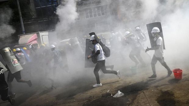 Protesters hold homemade shields as they run during a demonstration against the military coup in Yangon on March 3, 2021. (Photo by STR / AFP)