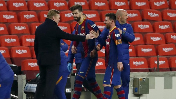 Barcelonas Lionel Messi shakes hands with Barcelonas head coach Ronald Koeman at the end of the the Copa del Rey semifinal, second leg, soccer match between FC Barcelona and Sevilla FC at the Camp Nou stadium in Barcelona, Spain, Wednesday March 3, 2021. Barcelona won 3-0. (AP Photo/Joan Monfort)