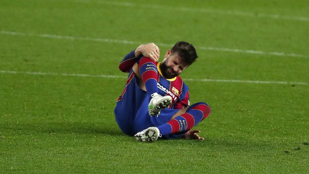 Barcelona's Gerard Pique holds his knee after getting injured during the the Copa del Rey semifinal, second leg, soccer match between FC Barcelona and Sevilla FC at the Camp Nou stadium in Barcelona, Spain, Wednesday March 3, 2021. (AP Photo/Joan Monfort)