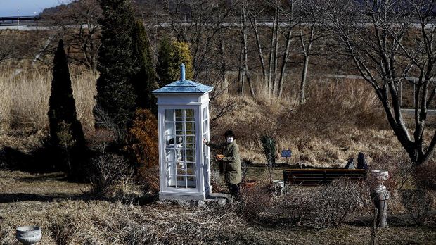 Tomoko Kumagai, 58, who lost her colleague in the March 11, 2011 earthquake and tsunami, visits Kaze-no-Denwa (the phone of the wind), a phone booth set up for people to call their deceased loved ones, ahead of the 10th anniversary the disaster, at Bell Gardia Kujira-yama in Otsuchi town, Iwate Prefecture, northern Japan February 28, 2021. REUTERS/Issei Kato     SEARCH 