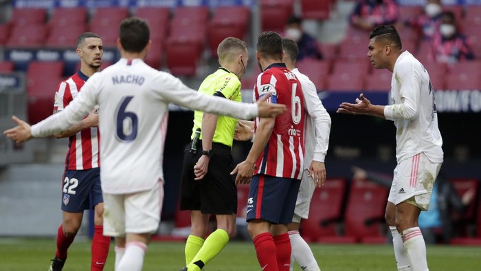 Real Madrids Nacho, left, and Casemiro, right, open their arms as they take on the referee during the Spanish La Liga soccer match between Atletico Madrid and Real Madrid at the Wanda Metropolitano stadium in Madrid, Spain, Sunday, March 7, 2021. (AP Photo/Manu Fernandez)