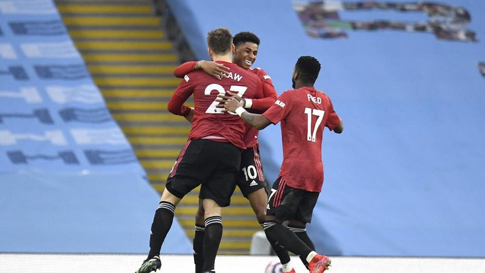 MANCHESTER, ENGLAND - MARCH 07: Luke Shaw of Manchester United celebrates with Marcus Rashford and Fred after scoring their sides second goal during the Premier League match between Manchester City and Manchester United at Etihad Stadium on March 07, 2021 in Manchester, England. Sporting stadiums around the UK remain under strict restrictions due to the Coronavirus Pandemic as Government social distancing laws prohibit fans inside venues resulting in games being played behind closed doors. (Photo by Peter Powell - Pool/Getty Images)