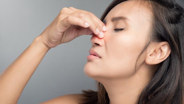 An Asian woman is hurting her nose because of the cold.