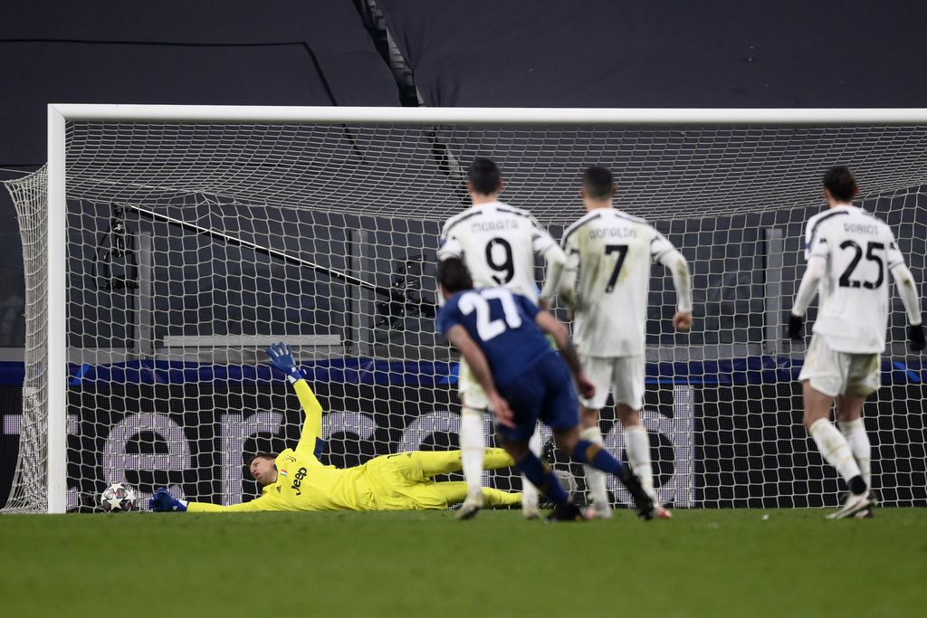 Juventus goalkeeper Wojciech Szczesny, left, cannot stop a goal from Porto's Sergio Oliveira (27) during the second leg of the Champions League round of 16 between Juventus and Porto in Turin, Italy , Tuesday, March 9, 2021.  (Fabio Ferrari / LaPresse via AP)