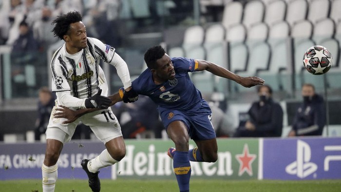 Juventus Juan Cuadrado fights for the ball with Portos Zaidu Sanusi, right, during the Champions League, round of 16, second leg, soccer match between Juventus and Porto in Turin, Italy, Tuesday, March 9, 2021. (AP Photo/Luca Bruno)