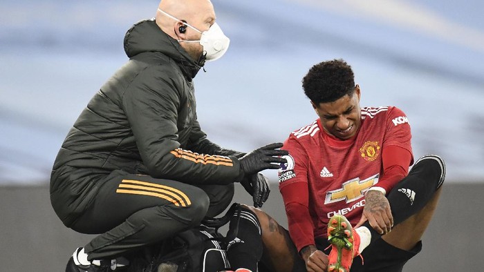 MANCHESTER, ENGLAND - MARCH 07: Marcus Rashford of Manchester United reacts as he receives medical treatment during the Premier League match between Manchester City and Manchester United at Etihad Stadium on March 07, 2021 in Manchester, England. Sporting stadiums around the UK remain under strict restrictions due to the Coronavirus Pandemic as Government social distancing laws prohibit fans inside venues resulting in games being played behind closed doors. (Photo by Peter Powell - Pool/Getty Images)