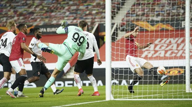 Manchester United's Harry Maguire, right, makes an attempt to score during the Europa League round of 16 first leg soccer match between Manchester United and AC Milan at Old Trafford in Manchester, England, Thursday, March 11, 2021. (AP Photo/Dave Thompson)