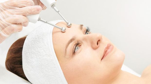 Microcurrent esthetics procedure. Beauty girl face. Cosmetology machine. Doctor hands. Two micro balls. Wrinkle reduction.