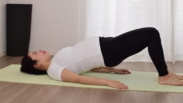 A young pregnant woman is doing fitness at home. It is important to exercise during pregnancy.