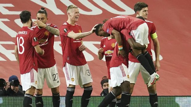 Manchester United players celebrate after Manchester United's Amad Diallo scored his side's opening goal during the Europa League round of 16 first leg soccer match between Manchester United and AC Milan at Old Trafford in Manchester, England, Thursday, March 11, 2021. (AP Photo/Dave Thompson)