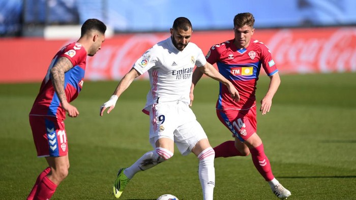 MADRID, SPAIN - MARCH 13: Karim Benzema of Real Madrid holds the ball whilst under pressure from Tete Morente and Guti of Elche CF during the La Liga Santander match between Real Madrid and Elche CF at Estadio Alfredo Di Stefano on March 13, 2021 in Madrid, Spain. Sporting stadiums around Spain remain under strict restrictions due to the Coronavirus Pandemic as Government social distancing laws prohibit fans inside venues resulting in games being played behind closed doors. (Photo by Denis Doyle/Getty Images)