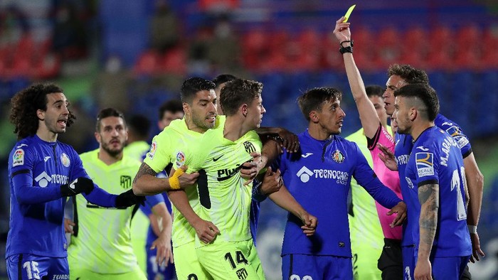 GETAFE, SPAIN - MARCH 13: Marcos Llorente of Atletico Madrid is held back by Luis Suarez of Atletico Madrid as he is shown a yellow card by referee Jose Maria Sanchez Martinez during the La Liga Santander match between Getafe CF and Atletico de Madrid at Coliseum Alfonso Perez on March 13, 2021 in Getafe, Spain. Sporting stadiums around Spain remain under strict restrictions due to the Coronavirus Pandemic as Government social distancing laws prohibit fans inside venues resulting in games being played behind closed doors. (Photo by Gonzalo Arroyo Moreno/Getty Images)