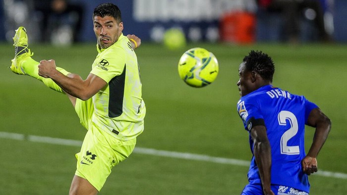 Atletico Madrids Luis Suarez, left, duels for the ball with Getafes Djene Dakonam during the Spanish La Liga soccer match between Getafe and Atletico Madrid at the Alfonso Perez stadium in Getafe, Spain, Saturday, March 13, 2021. (AP Photo/Manu Fernandez)