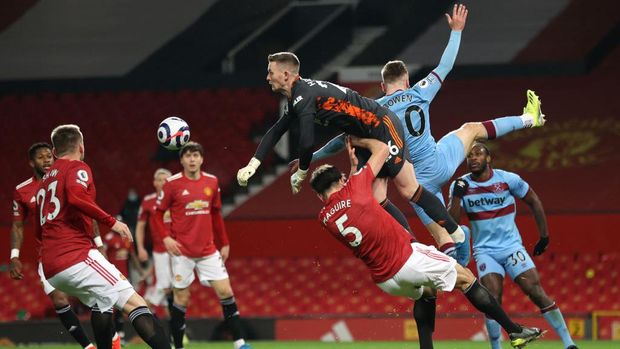 MANCHESTER, ENGLAND - MARCH 14: Dean Henderson of Manchester United punches the ball away as he collides with team mate Harry Maguire and Jarrod Bowen of West Ham United during the Premier League match between Manchester United and West Ham United at Old Trafford on March 14, 2021 in Manchester, England. Sporting stadiums around the UK remain under strict restrictions due to the Coronavirus Pandemic as Government social distancing laws prohibit fans inside venues resulting in games being played behind closed doors. (Photo by Clive Brunskill/Getty Images)