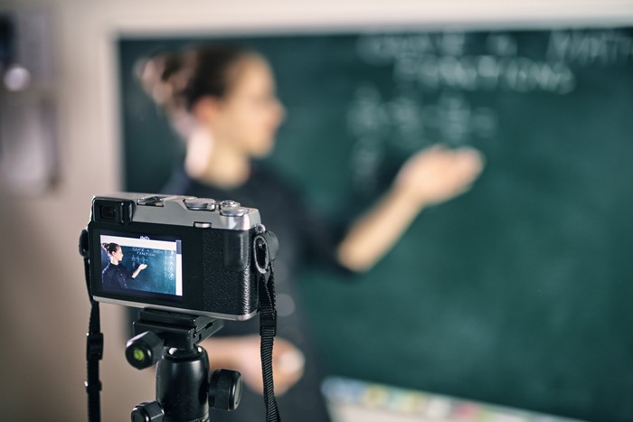 Young teacher teaching remotely using camera to stream lesson.