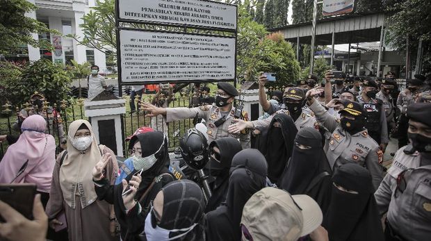 Personel Kepolisian membubarkan massa pendukung saat berlangsungnya sidang perdana kasus pelanggaran protokol kesehatan dengan terdakwa Rizieq Shihab di Pengadilan Negeri (PN) Jakarta Timur, Jakarta, Selasa (16/3/2021). Sidang tersebut beragendakan pembacaan dakwaan dari Jaksa Penuntut Umum (JPU). ANTARA FOTO/Dhemas Reviyanto/rwa.