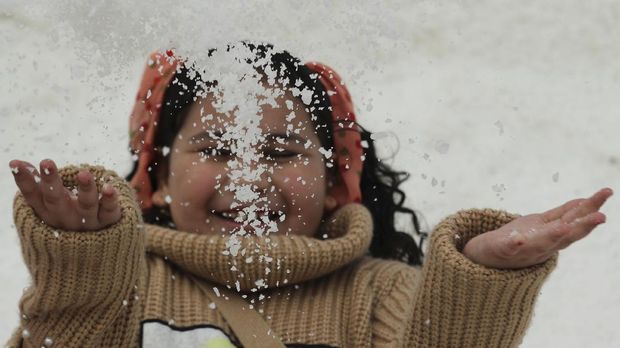 A girl throws up some salt crystals as she visits the small salt hills in the canal city of Port Fouad, Egypt March 12, 2021. Picture taken March 12, 2021. REUTERS/Mohamed Abd El Ghany