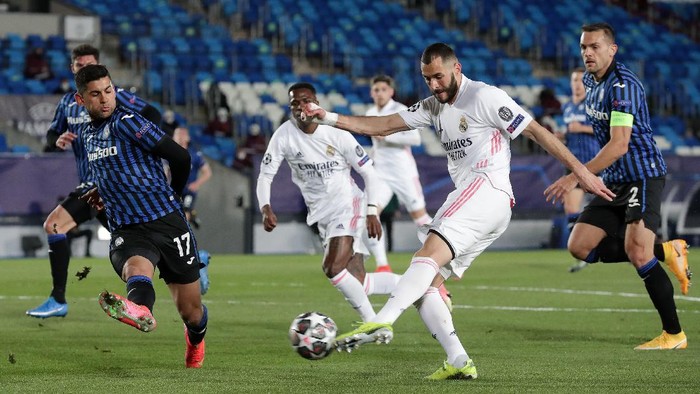 MADRID, SPAIN - MARCH 16: Karim Benzema of Real Madrid shoots whilst under pressure from Cristian Romero of Atalanta B.C. during the UEFA Champions League Round of 16 match between Real Madrid and Atalanta at Estadio Alfredo Di Stefano on March 16, 2021 in Madrid, Spain. Sporting stadiums around Spain remain under strict restrictions due to the Coronavirus Pandemic as Government social distancing laws prohibit fans inside venues resulting in games being played behind closed doors. (Photo by Gonzalo Arroyo Moreno/Getty Images)
