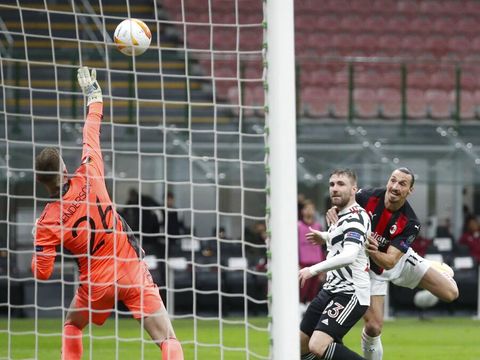 Manchester United's goalkeeper Dean Henderson, left, deflects a shot away from the goal from AC Milan's Zlatan Ibrahimovic, right, during the Europa League round of 16 second leg soccer match between AC Milan and Manchester United at the San Siro Stadium, in Milan, Italy, Thursday, March 18, 2021. (AP Photo/Antonio Calanni)