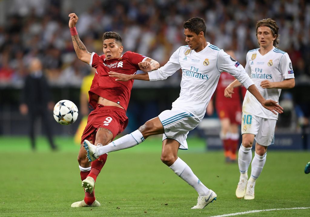 KIEV, UKRAINE - MAY 26: Raphael Varane of Real Madrid is challenged by Roberto Firmino of Liverpool during the UEFA Champions League Final between Real Madrid and Liverpool at NSC Olimpiyskiy Stadium on May 26, 2018 in Kiev, Ukraine.  (Photo by Laurence Griffiths/Getty Images)
