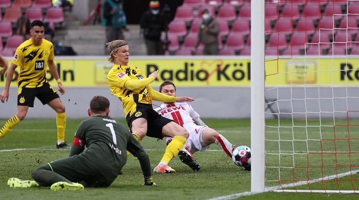 COLOGNE, GERMANY - MARCH 20: Erling Haaland of Borussia Dortmund scores their sides second goal as Benno Schmitz of 1.FC Koeln challenges during the Bundesliga match between 1. FC Koeln and Borussia Dortmund at RheinEnergieStadion on March 20, 2021 in Cologne, Germany. Sporting stadiums around Germany remain under strict restrictions due to the Coronavirus Pandemic as Government social distancing laws prohibit fans inside venues resulting in games being played behind closed doors. (Photo by Lars Baron/Getty Images)