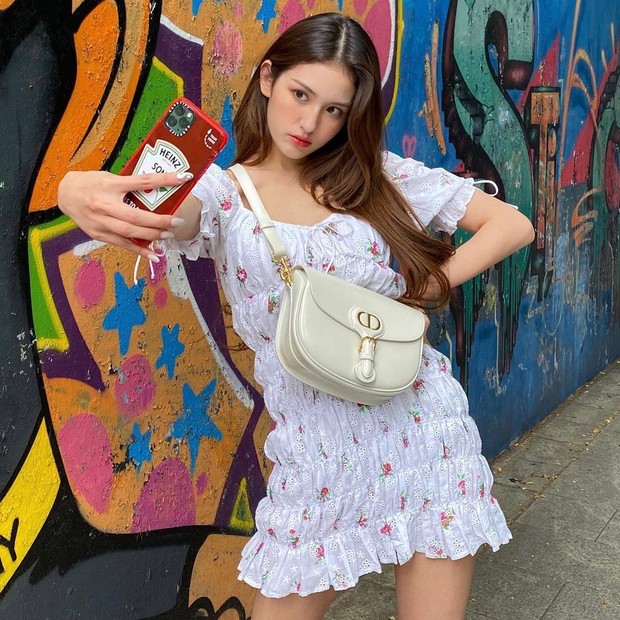 Smocked Floral Dress/instagram.com/somsomi0309 Somi mengenakan smocked dress berwarna putih dengan motif bunga-bunga. Meski tidak menambahkan aksesoris apapun, kamu akan tetap tampil cantik dan menarik hanya dengan outfit ini.