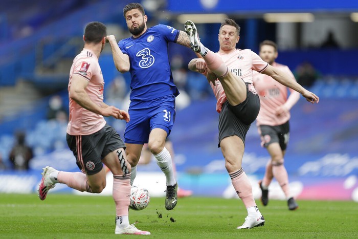 Chelseas Olivier Giroud, center, is challenged by Sheffield Uniteds Phil Jagielka, right, during the English FA Cup quarterfinal soccer match between Chelsea and Sheffield United at the Stamford Bridge stadium in London, Sunday, March 21, 2021. (AP Photo/Kirsty Wigglesworth)