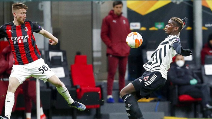 Manchester Uniteds Paul Pogba, right, attempts to control the ball as AC Milans Alexis Saelemaekers, left, watches during the Europa League round of 16 second leg soccer match between AC Milan and Manchester United at the San Siro Stadium, in Milan, Italy, Thursday, March 18, 2021. (AP Photo/Antonio Calanni)