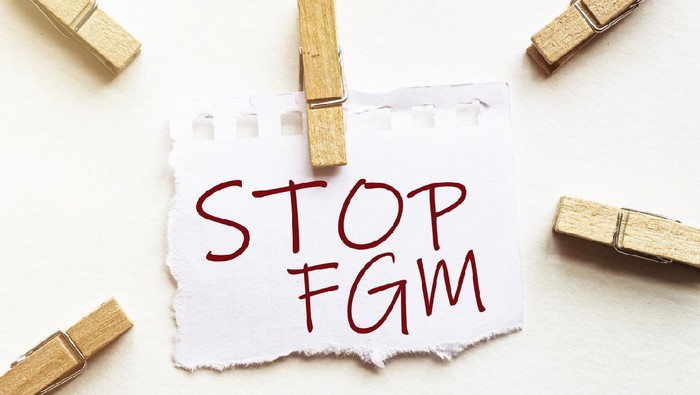 Ilustrasi kampanye anti sunat perempuan white paper with text Stop Fgm with clothespins on white background