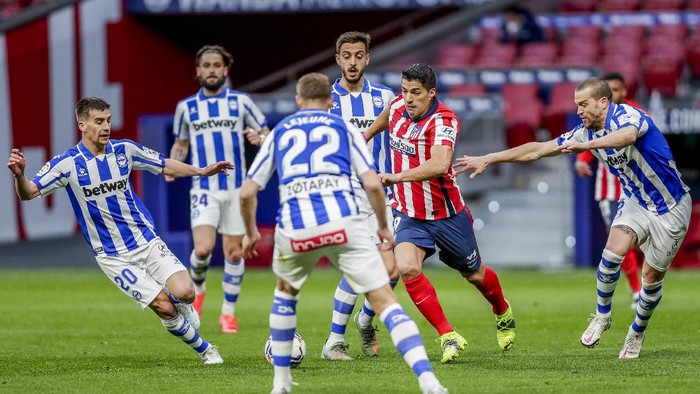 Atletico Madrids Luis Suarez, center right, is surrounded by Alaves players during the Spanish La Liga soccer match between Atletico Madrid and Alaves at the Wanda Metropolitano stadium in Madrid, Spain, Sunday, March 21, 2021. (AP Photo/Manu Fernandez)