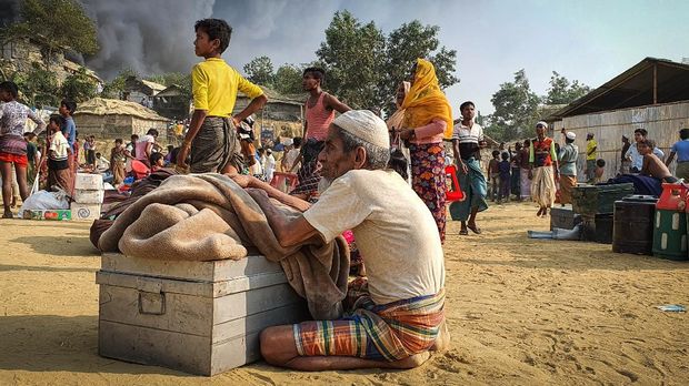 Rohingya refugees salvage their belongings and watch smoke rising following a fire at the Rohingya refugee camp in Balukhali, southern Bangladesh, Monday, March 22, 2021. The fire destroyed hundreds of shelters and left thousands homeless, officials and witnesses said. (AP Photo/ Shafiqur Rahman)