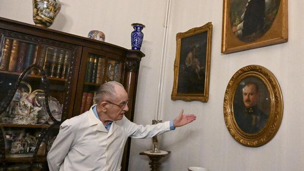 97-year-old Hungarian doctor Istvan Kormendi shows his military doctor father's portrait, while a portrait of him is seen on the right, in his doctor's office at his home in Budapest on March 22, 2021. - Hungarian family doctor and Holocaust survivor Istvan Kormendi, widely considered the oldest in his profession, is still practising his 