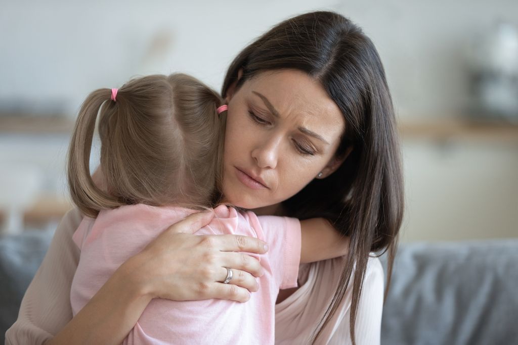 Worried young foster care parent mother comforting solacing embrace adopted little child daughter give care and protection at home, loving concerned adult mom hug sad small girl consoling kid concept