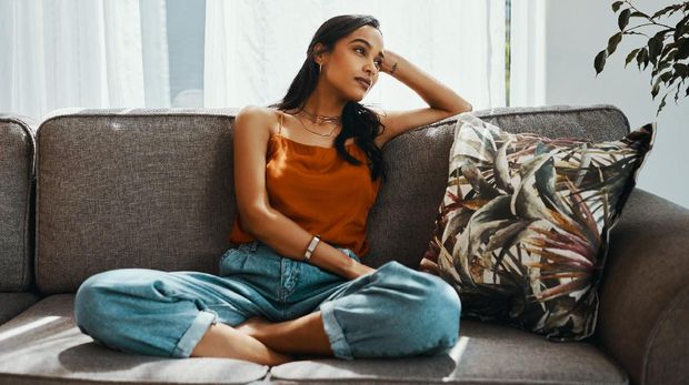 Shot of a young woman looking thoughtful while relaxing on the sofa at home