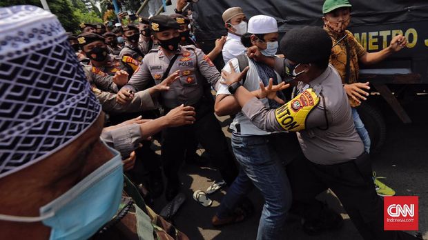 Petugas Kepolisian membubarkan massa pendukung saat berlangsungnya sidang tatap muka lanjutan kasus pelanggaran protokol kesehatan dengan terdakwa Rizieq Shihab di Pengadilan Negeri (PN) Jakarta Timur, Jakarta, Jumat, 26 Maret 2021. CNN Indonesia/Adhi Wicaksono