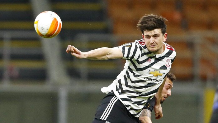 Manchester Uniteds Harry Maguire, left, heads the ball away from and AC Milans Hakan Calhanoglu during the Europa League round of 16 second leg soccer match between AC Milan and Manchester United at the San Siro Stadium, in Milan, Italy, Thursday, March 18, 2021. (AP Photo/Antonio Calanni)