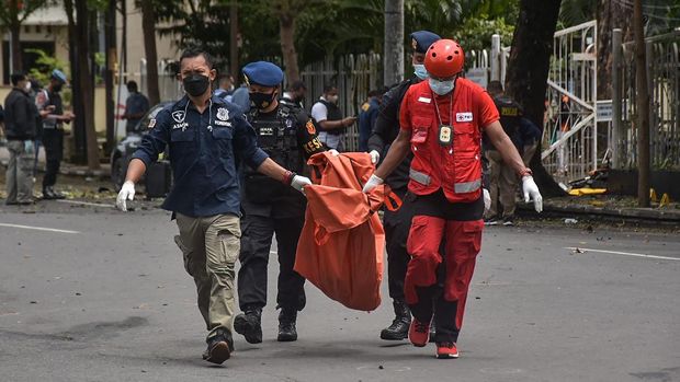Indonesian police carry a bag with the remains of a suspected suicide bomber after an explosion outside a church in Makassar on March 28, 2021. (Photo by INDRA ABRIYANTO / AFP)