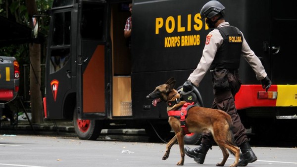 Anggota polisi berjalan dengan anjing pelacak saat mengumpulkan sisa serpihan ledakan bom bunuh diri di depan Gereja Katedral Makassar, Sulawesi Selatan, Senin (29/3/2021). Kepolisian masih melakukan olah TKP serta mengumpulkan serpihan sisa ledakan pada hari kedua pascaledakan bom bunuh diri yang terjadi pada Minggu (28/3/2021) di depan gereja tersebut. ANTARA FOTO/Arnas Padda/yu/aww.