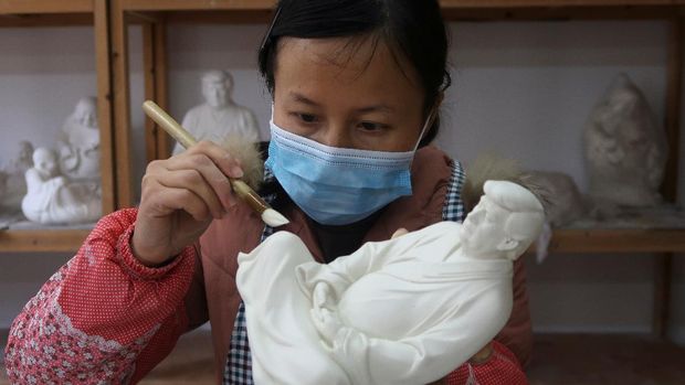 An employee applies finishing touches to a statue depicting former U.S. President Donald Trump in a Buddhist meditative pose, by Chinese designer Hong Jinshi, at a workshop in Dehua, Fujian province, China March 24, 2021. Picture taken March 24, 2021. REUTERS/Martin Pollard