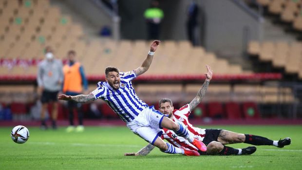 SEVILLE, SPAIN - APRIL 03: Inigo Martinez of Athletic Bilbao tackles  Portu of Real Sociedad which leads to a penalty decision and a red card which was then overturned to a yellow card by VAR during the Copa Del Rey Final match between Real Sociedad and Athletic Club at Estadio de La Cartuja on April 03, 2021 in Seville, Spain. Sporting stadiums around Spain remain under strict restrictions due to the Coronavirus Pandemic as Government social distancing laws prohibit fans inside venues resulting in games being played behind closed doors. (Photo by Fran Santiago/Getty Images)