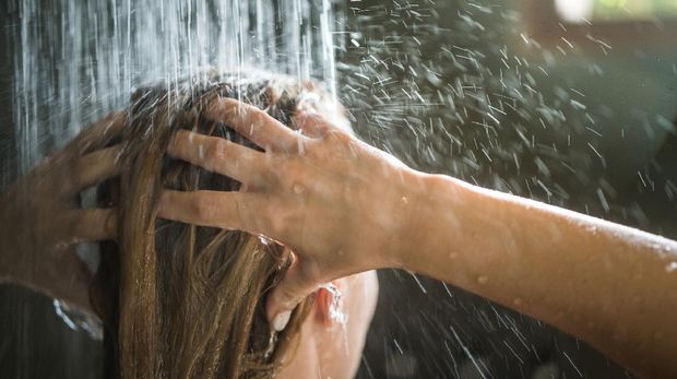 Tampilan jarak dekat dari seorang wanita mencuci rambutnya saat mandi di pagi hari.