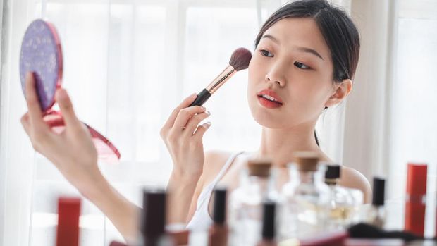 Young beautiful Asian woman applying cosmetics make up on her face, health beauty skin care and make up concept