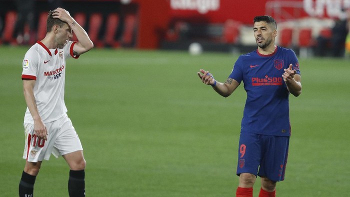 Atletico Madrids Luis Suarez, right, reacts during a Spanish La Liga soccer match between Sevilla and Atletico de Madrid at the Ramon Sanchez-Pizjuan stadium in Seville, Spain, Sunday, April 4, 2021. (AP Photo/Angel Fernandez)